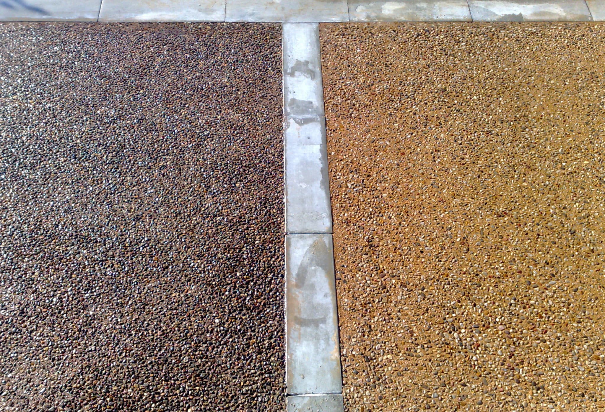 Dos paños contiguos de hormigón lavado, uno de árido oscuro y otro dorado, separados por una banda de piedra.