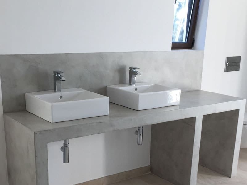 Encimera de baño de microcemento con dos lavabos sobre encimera y frente continuo sin juntas.